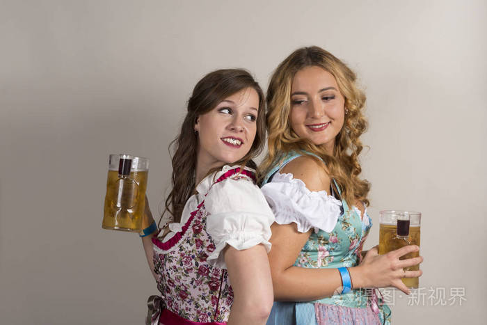 在裙与啤酒杯子在手里的两个漂亮的女招待