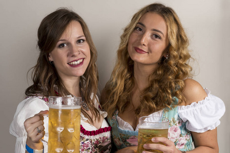 两个女孩在传统的德国服装与手中的啤酒