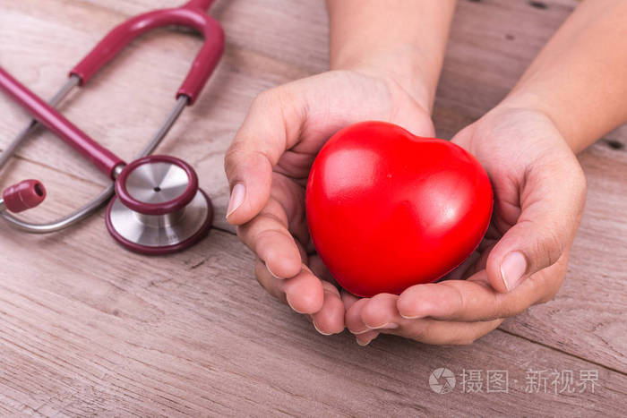 检查心脏概念: 女人手里拿着红色的心和 stethosc