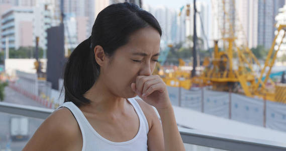 女人咳嗽在户外在建筑工地旁边图片