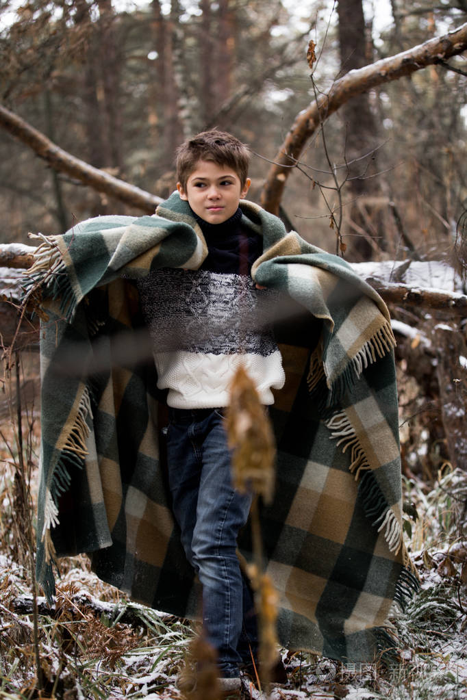 在格子中的一个小男孩走在秋天的树林的雪.独自一人