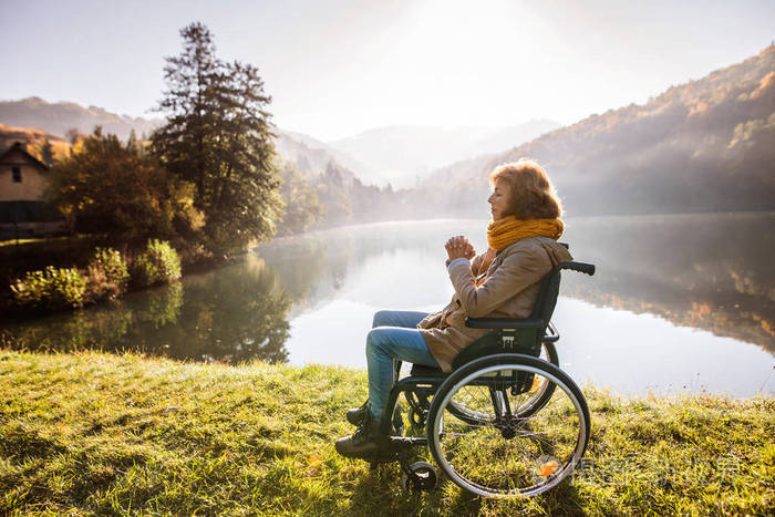 高级的女人坐在轮椅上在秋天的性质