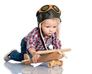 一个小男孩在飞行员帽，手里的木制飞机