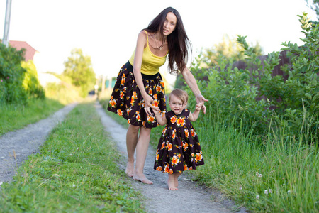 赤脚走在一条乡间小路在同一件衣服上的妈妈和宝贝女孩