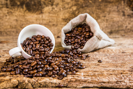 咖啡豆在白色的杯子里。咖啡豆在一个木制的背景上。一袋咖啡豆。黑暗的背景