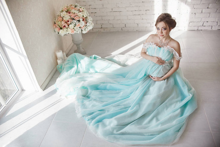 孕妇一个新生儿九月的怀孕散步在公园秋天的天气穿着薄的浅蓝色礼服和