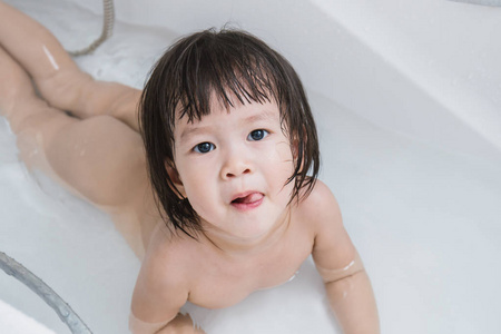 快乐的亚洲宝贝在洗澡和看镜头图片