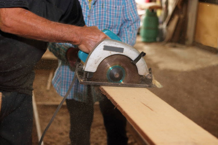 名灌木工人电动圆锯机是被锯掉了一块木头高级名工人在木工车间照片