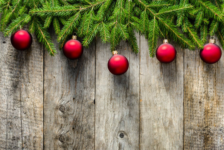 质朴的圣诞贺卡, 挂在木质背景的冷杉树枝上的红色小