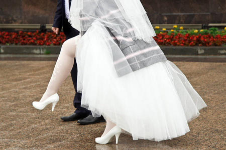 新娘在街上调整长袜.婚纱,长袜和白鞋照片