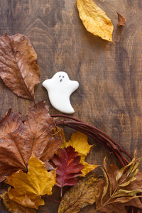 万圣节姜饼鬼, 装饰着秋天的树叶, 在一个木制的背景