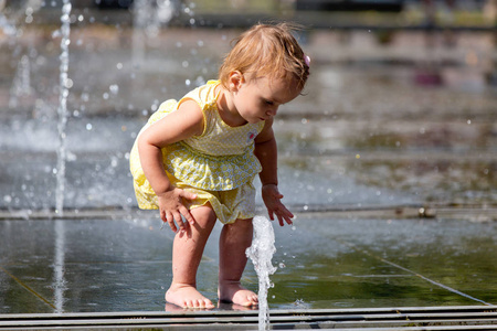 可爱的小女孩玩水射流的喷泉