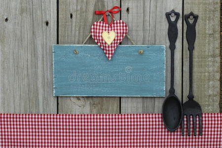 古色古香的空白蓝色心形标牌，方格桌布和铸铁勺子和叉子
