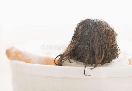 在浴缸里放松的年轻女子。后视图