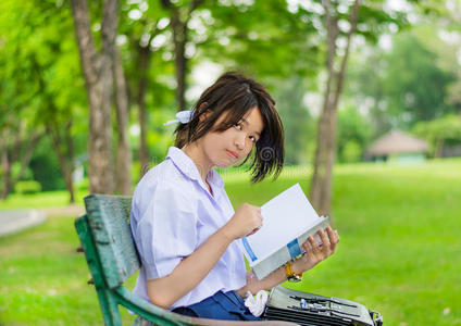 可爱的泰国女学生在长凳上学习