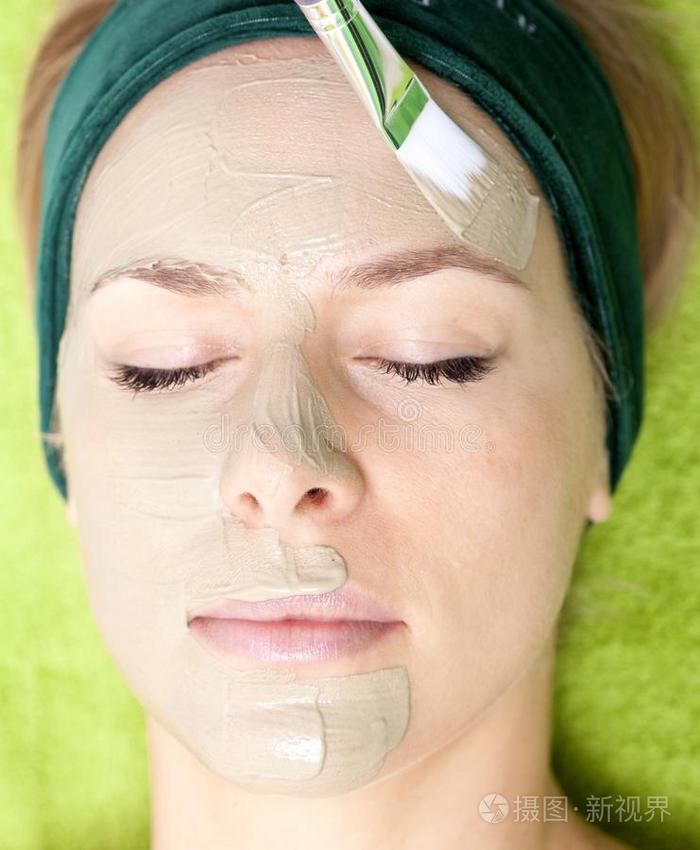 美容院化妆师在女性脸上涂面膜