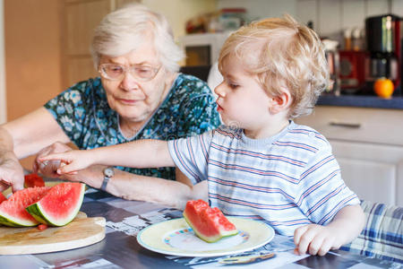 小男孩和他的曾祖母在吃西瓜