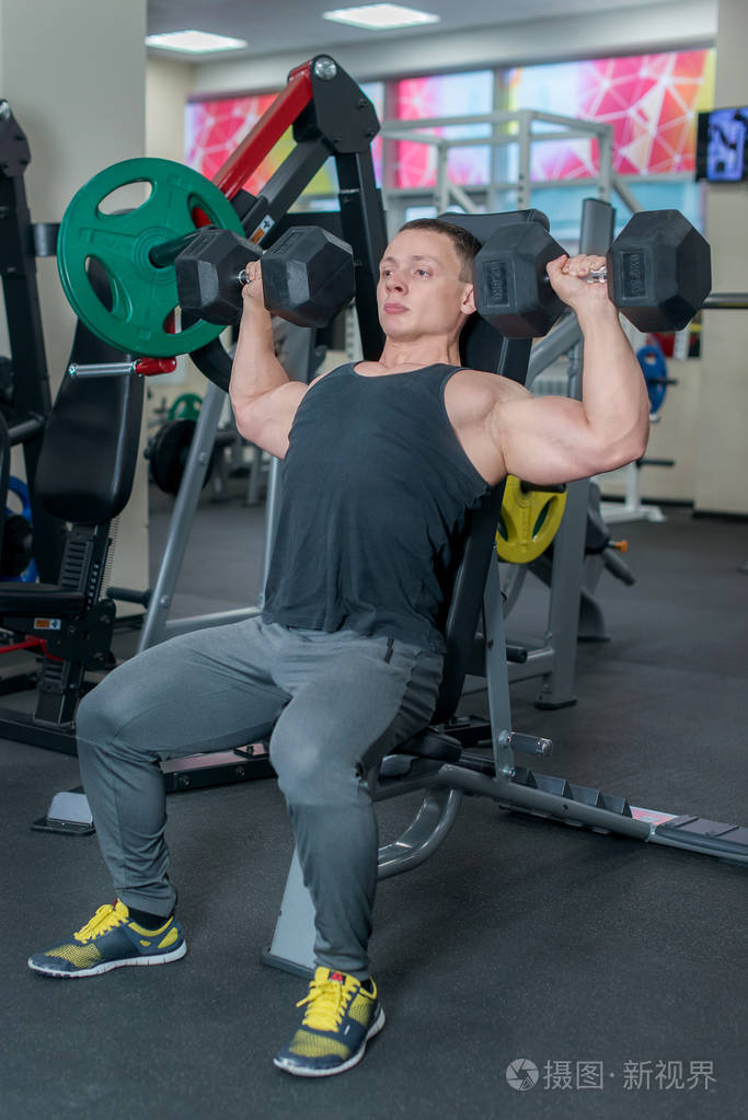 体育概念.健美运动员在健身房用哑铃锻炼