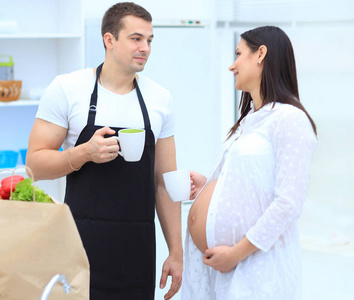 丈夫和他怀孕的妻子与一杯可可站在厨房