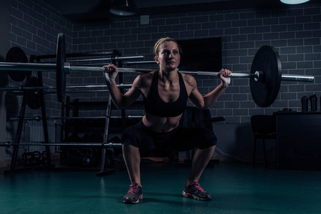 Crossfit 肌肉强壮的女子蹲在健身房重