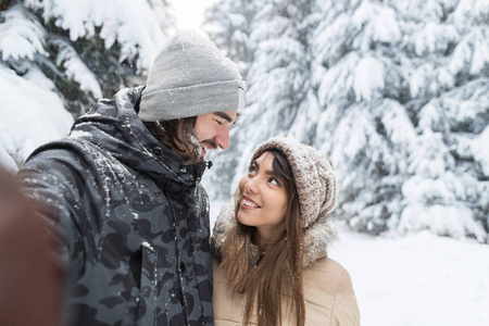 人采取自拍相片年轻浪漫夫妇微笑雪森林室外