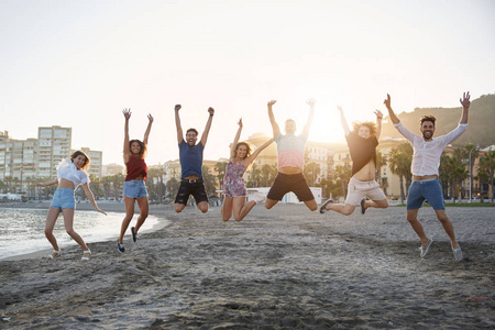 一群快乐的朋友在沙滩上跳跃