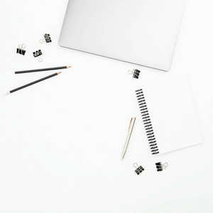 办公室桌面工作区，白色背景上有银色笔记本电脑和笔。 上面的风景。 平躺着