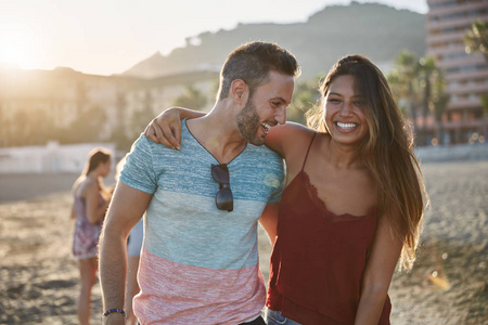 年轻快乐的情侣在沙滩上互相拥抱欢笑