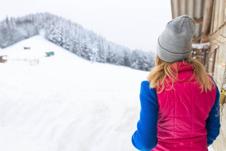 年轻的女孩看着白雪皑皑的冬天森林 Viggale 木乡间别墅度假村
