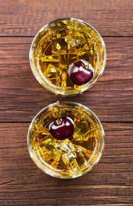 鸡尾酒从威士忌与樱桃在两个玻璃的木背
