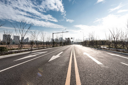 空的沥青路穿过现代城市，蓝天