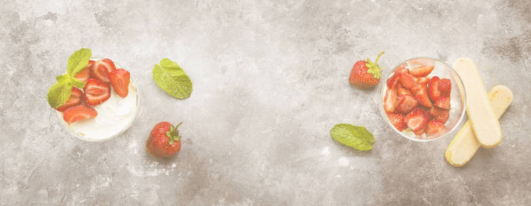 甜点提拉米苏与草莓在灰色背景。顶部视图