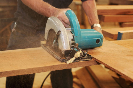 木头切割电圆锯切割一块木头的高级木匠木工车间的手照片