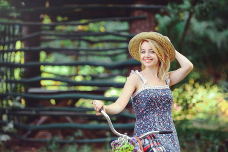 一个健康的女人美丽的夏天模型女孩与明亮的颜色自行车森林和篮子。休闲风格