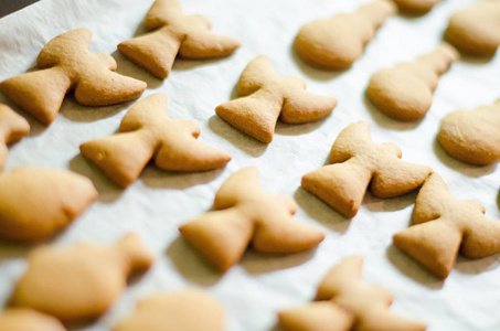 一套圣诞主题形状的饼干在白色的烹饪纸背景。天使, 雪人和鱼