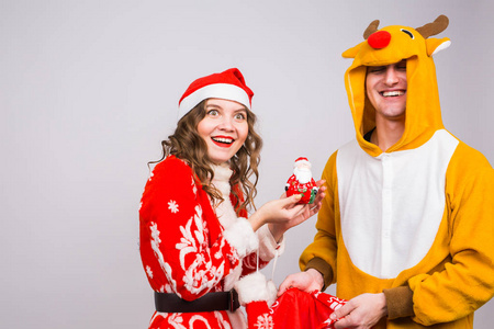 幸福的年轻女人在圣诞老人的帽子和嘉年华服装的鹿的人。乐趣 假日 笑话和圣诞节的概念