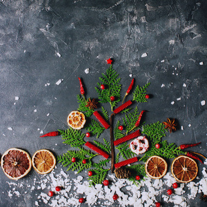季节性冬季装饰, 圣诞树, 糖果, 干桔子, 蔓越莓和香料在黑暗的石头桌上平的放置