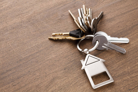 一串钥匙与房子形状的钥匙扣在白色木头