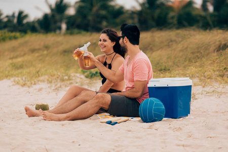 夫妇喝啤酒和在海滩上玩的乐趣