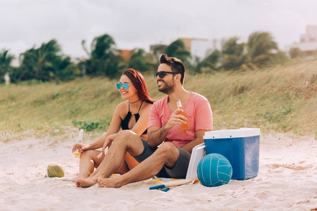 夫妇喝啤酒和在海滩上玩的乐趣