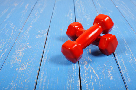 运动与健身木制背景下的两个红色哑铃