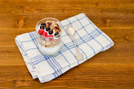 一杯酸奶, 用燕麦片和浆果放在木桌上。传统美式早餐