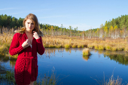 年轻女孩在红色开衫反对秋天风景的背景