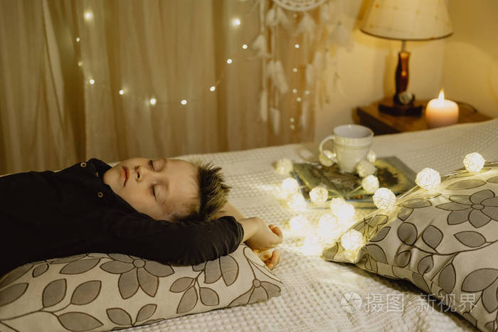 睡觉的男孩躺在床上晚上在黑暗中对backgroun