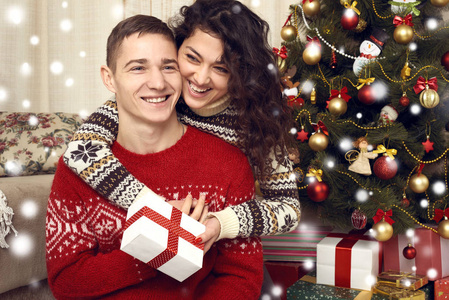 幸福的夫妇在圣诞节装饰在家中赠送礼物。新年前夕, ornated 枞树。寒假与爱情观