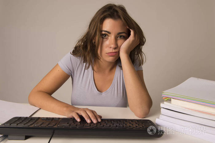 年轻有吸引力的学生女孩或工作的妇女坐在办公桌上的压力看起来疲惫