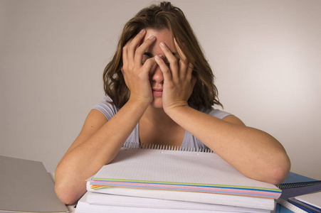 年轻漂亮, 美丽的疲惫的学生女孩倚在书本堆睡累了, 学习后疲惫照片