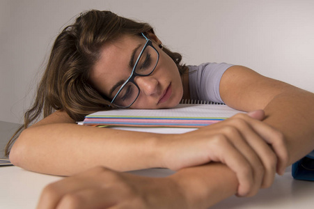 年轻漂亮, 美丽的疲惫的学生女孩倚在书本堆睡累了, 学习后疲惫