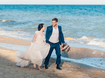 新婚夫妇，新郎和新娘的婚纱离大海很近在海边