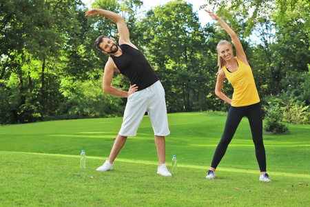 年轻运动的夫妇在绿色公园做运动